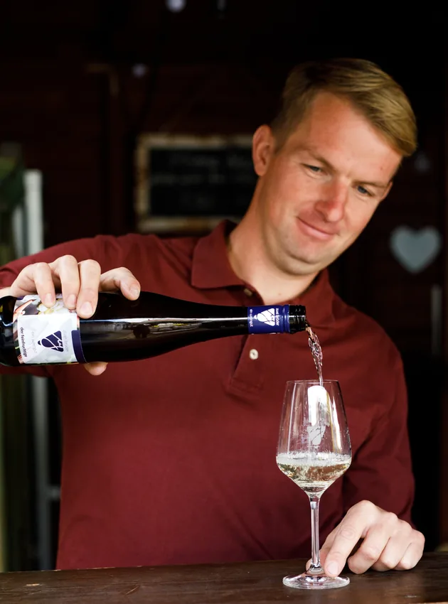 Wein vom Weingut Jonas wird eingeschenkt, auf dem Flaschenetikett das J-Logo