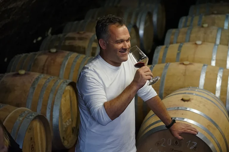 Markus Busch vom Weingut Karl Busch mit einem Glas Wein zwischen den Holzfässern im Gewölbekeller